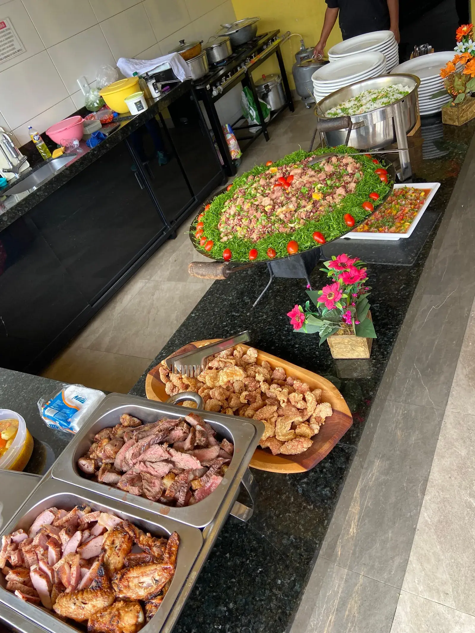 Buffet montado na bancada: tropeiro com couve, vinagrete, torresmo e carnes nas cubas