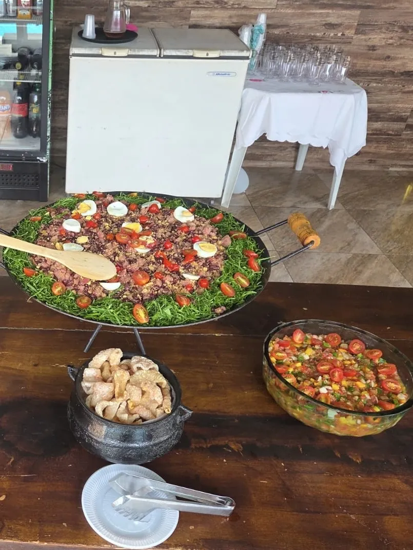 Tropeiro com couve e ovos, torresmo e vinagrete na mesa de madeira
